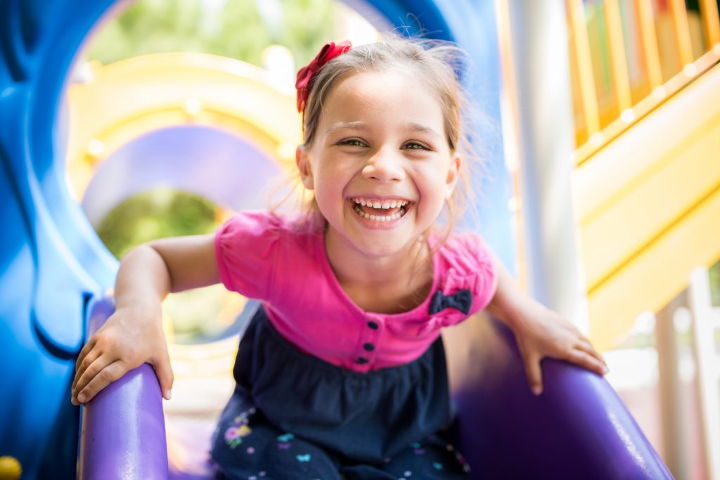 little girl playing on a slide at a playground outdoors